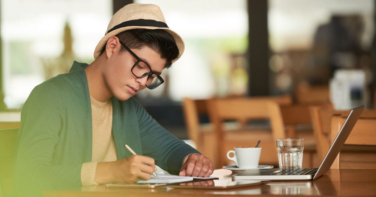 Asian man writing in a cafe setting